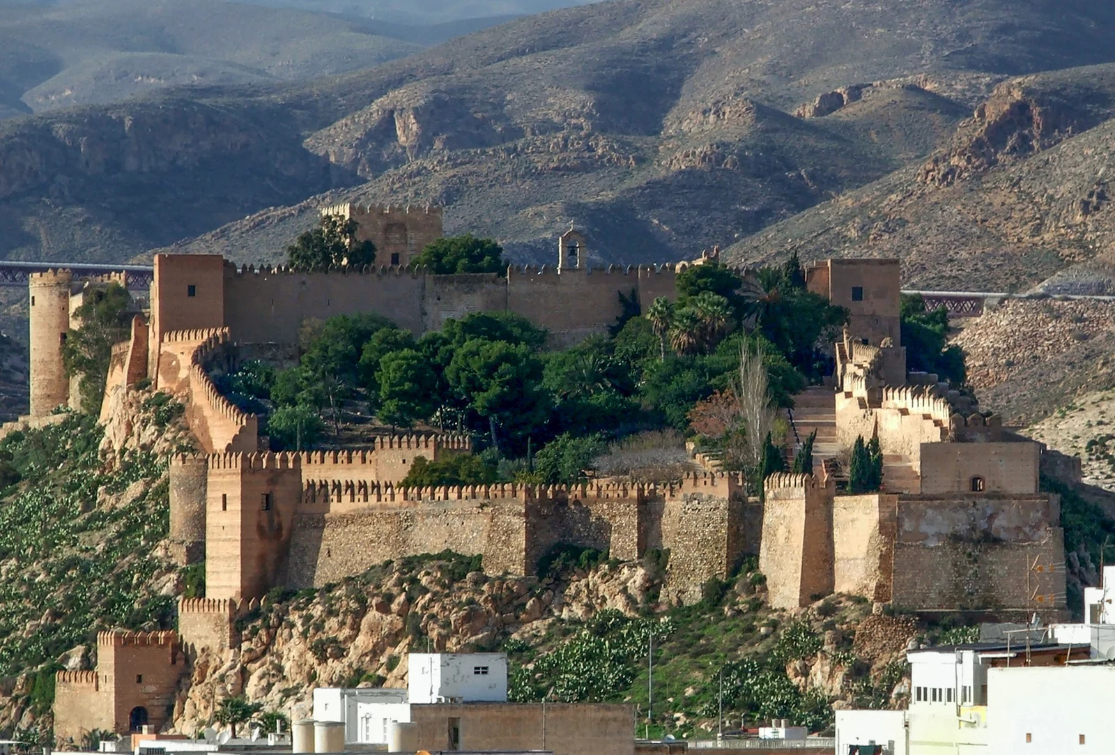 Murallas, torres y jardines de la Alcazaba de Almería vistos desde el este, con montañas al fondo.