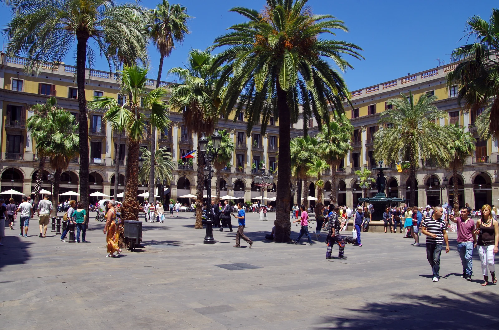 Palm trees, arcaded facades and people in Plaça Reial in Barcelona.