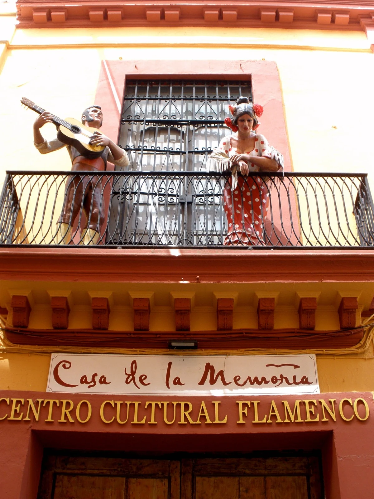 Casa de la Memoria facade with its sign and decorative flamenco figures on the balcony in Seville.