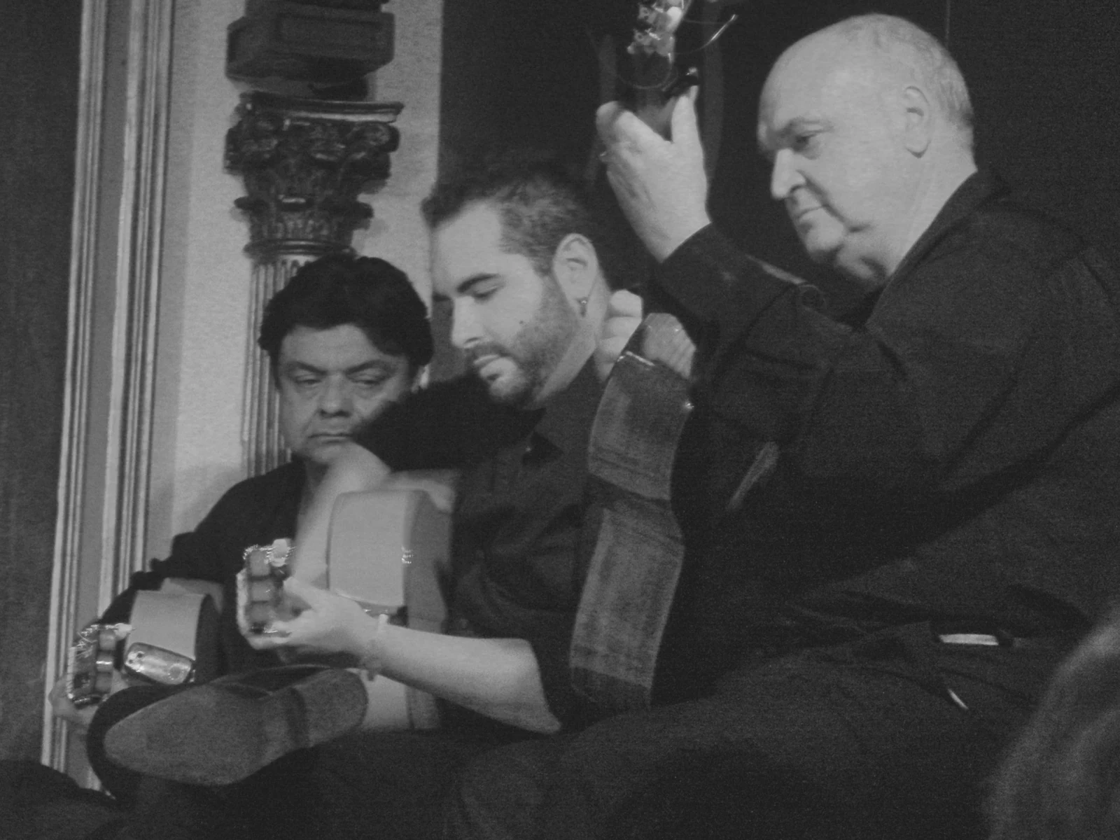 Black-and-white historical photo of seated flamenco musicians with guitars at Corral de la Morería in Madrid.